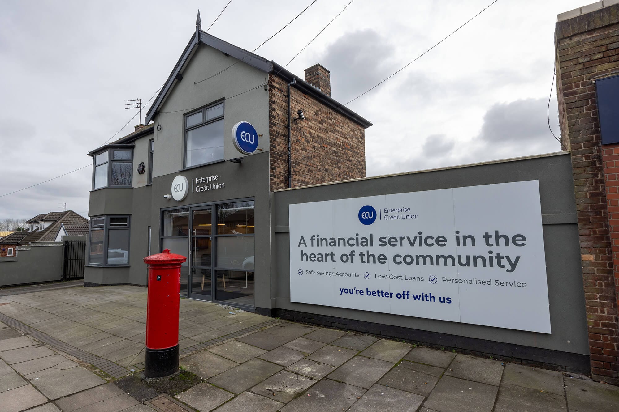 Exterior of an Enterprise Credit Union branch with large branding on the wall and a red post box on the pavement outside.