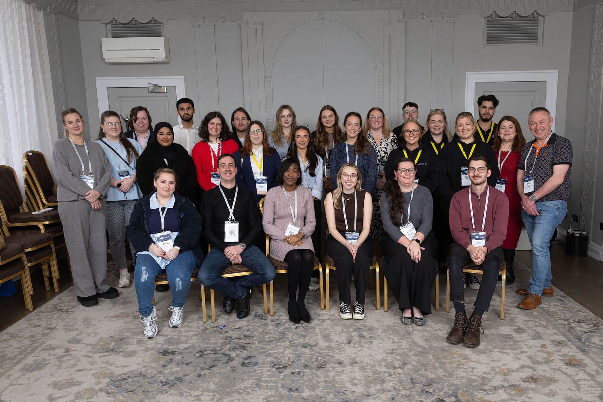 A large group of young professionals posing together in a conference room for a group photo.